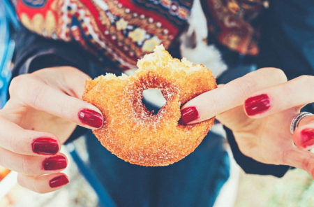 is-it-okay-to-have-a-cheat-day-marissa-vicario-health-coach-opinion - woman holding doughnut