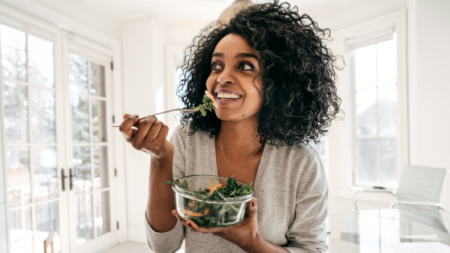 A woman eats a salad while figuring out her macros